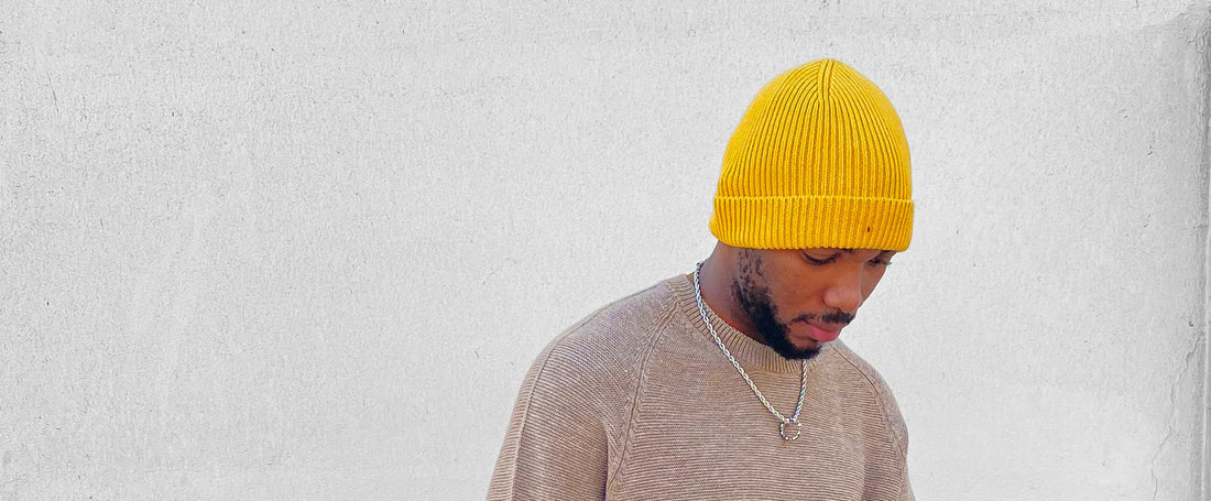 Young black man wearing a yellow toque and grey knitted sweater